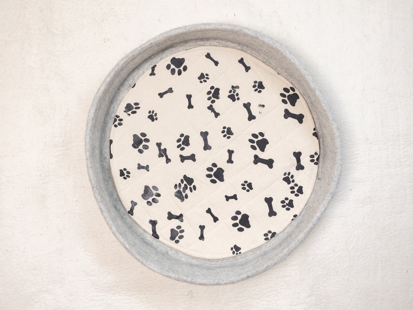 round grey dog bed with black paw print patterns in white cushion from top