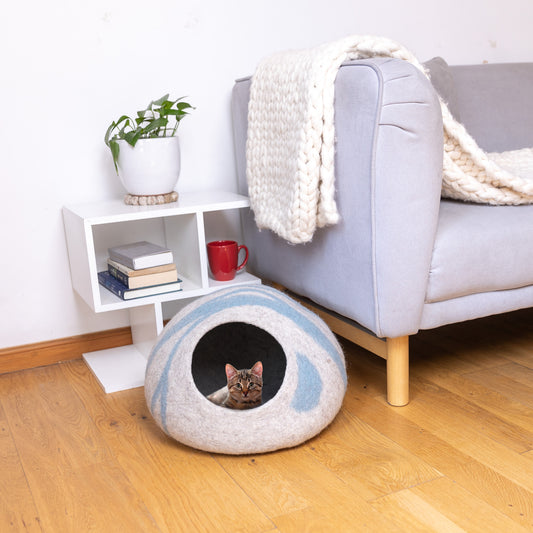 Cat relaxing inside blue stripe felt cat cave in modern living room