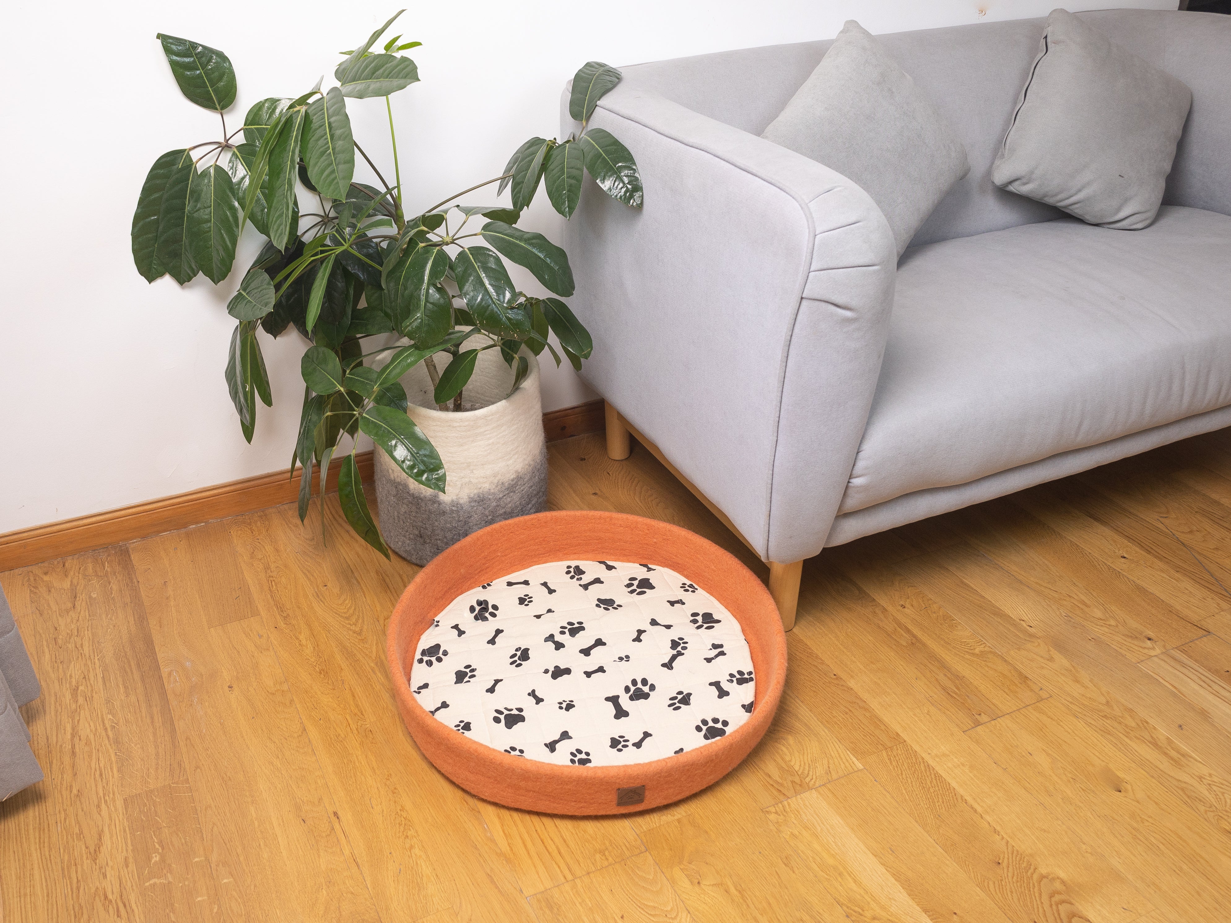 orange felt round dog bed with black paw and bones print patterns cushion, felt dog bed on floor