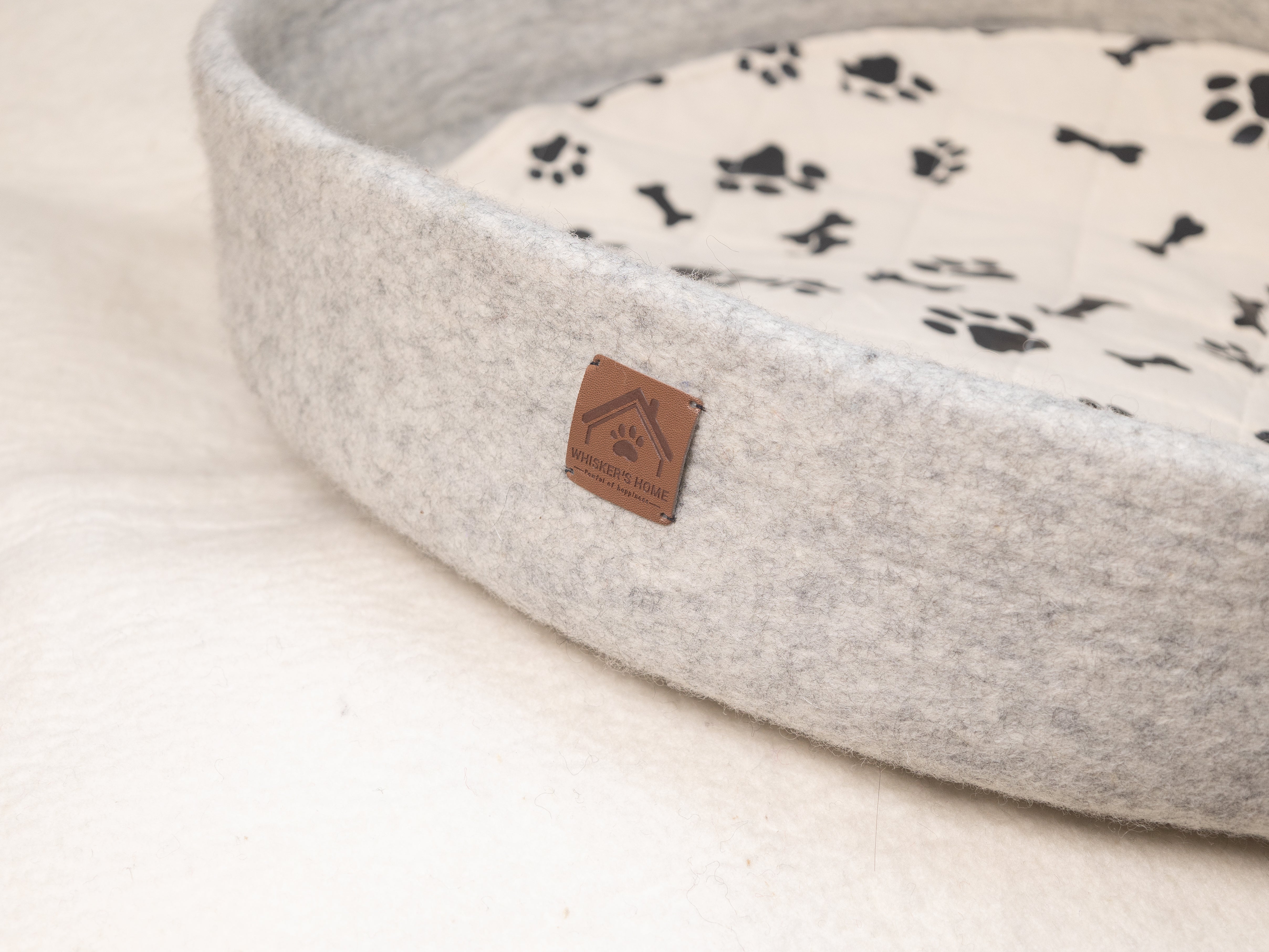 grey round wool dog bed with whisker's home tag