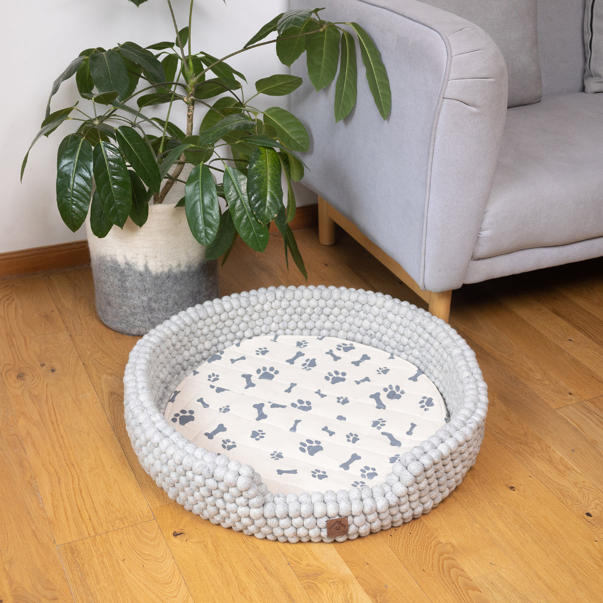 grey felt ball dog bed in living space around sofa and felt basket 