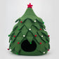 Green felt Christmas tree-shaped pet bed with red and white decorations on a light gray background