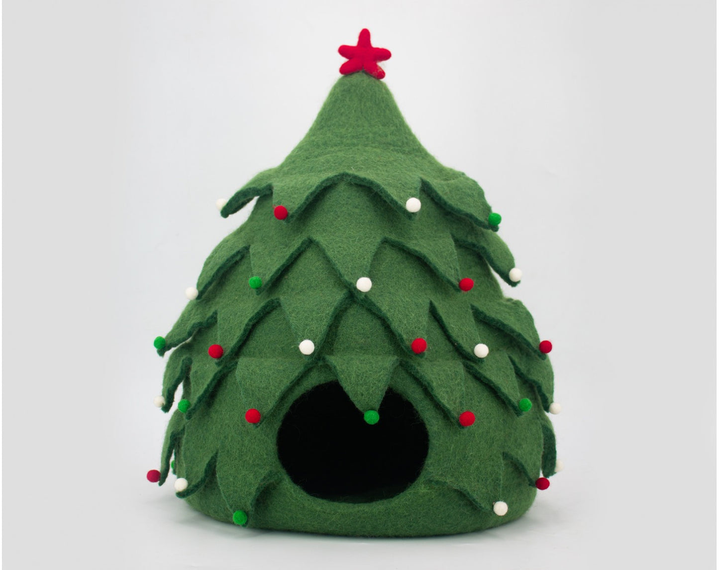 Green felt Christmas tree-shaped pet bed with red and white decorations on a light gray background