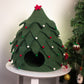 Green felt Christmas tree-shaped pet house with decorative lights and ornaments on a white surface.