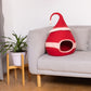Red gnome-shaped pet bed on a light gray sofa with a plant in the background